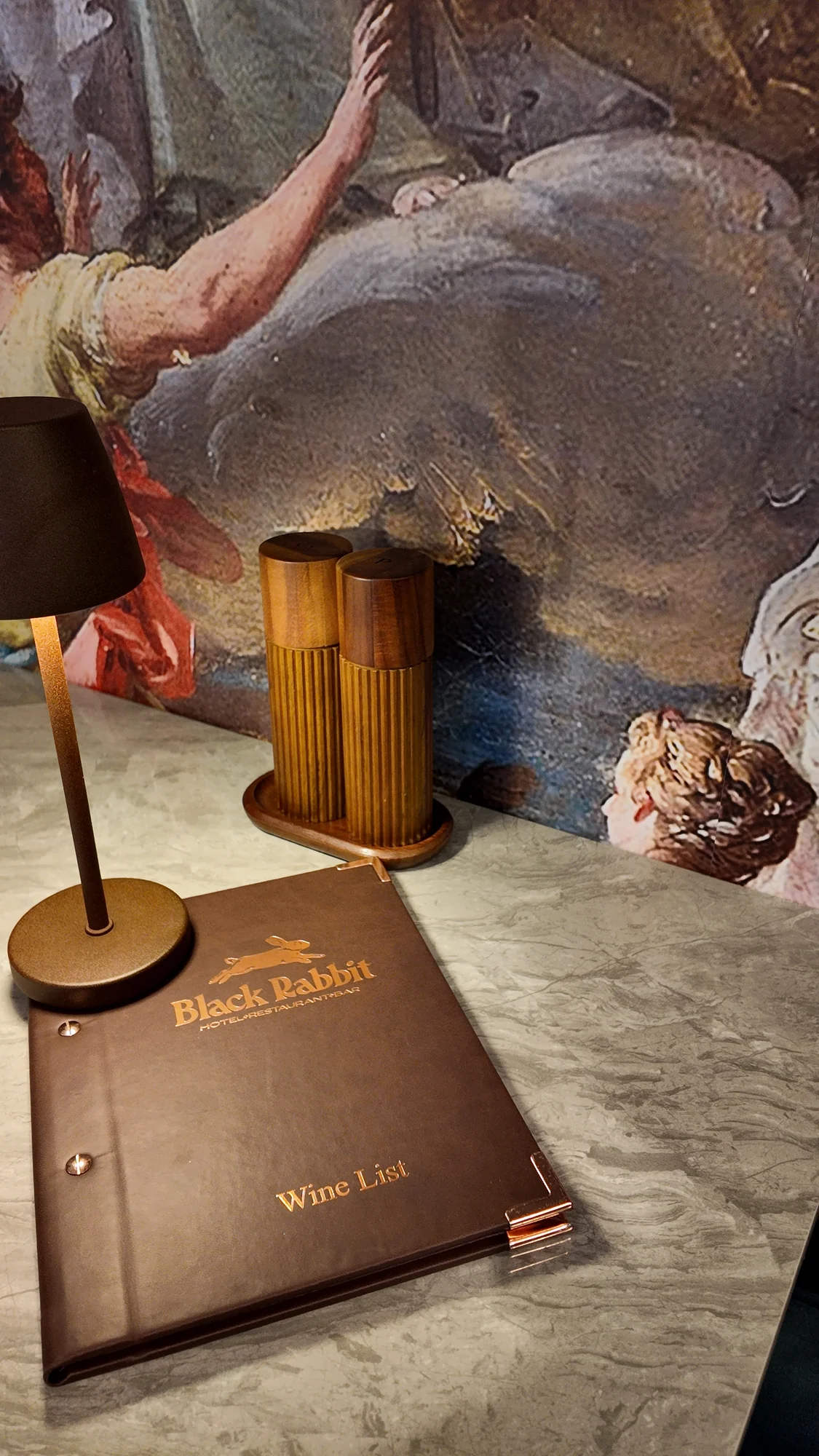 Black Rabbit wine list beside a table lamp and painted mural